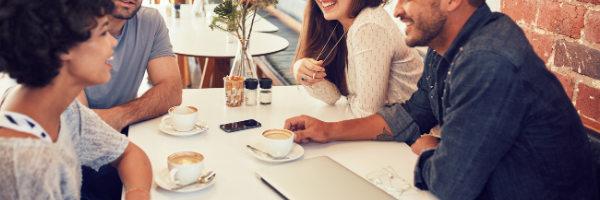 group of 4 sitting with coffee drinks during work