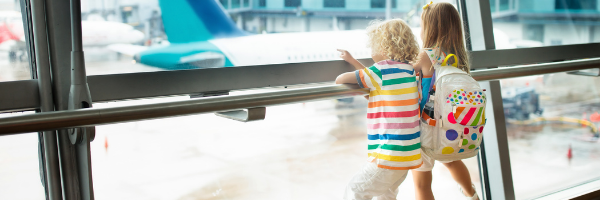 Two kids looking out the window at a plane