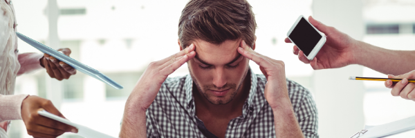 man with headache surrounded by technology