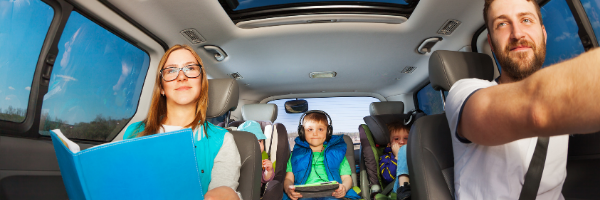 family of five in car with book and tablet