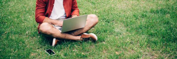 man sitting in grass on computer