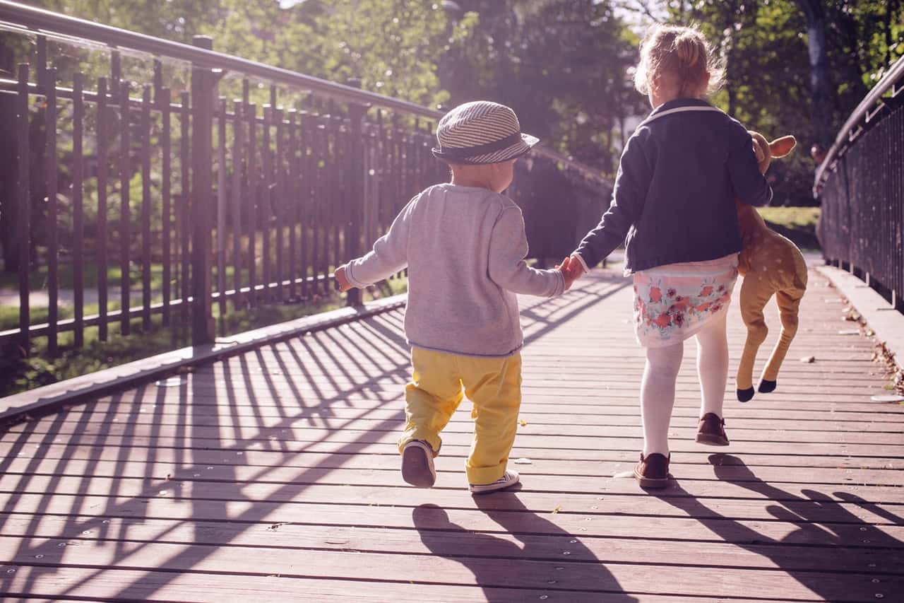 two young kids walking on bridge