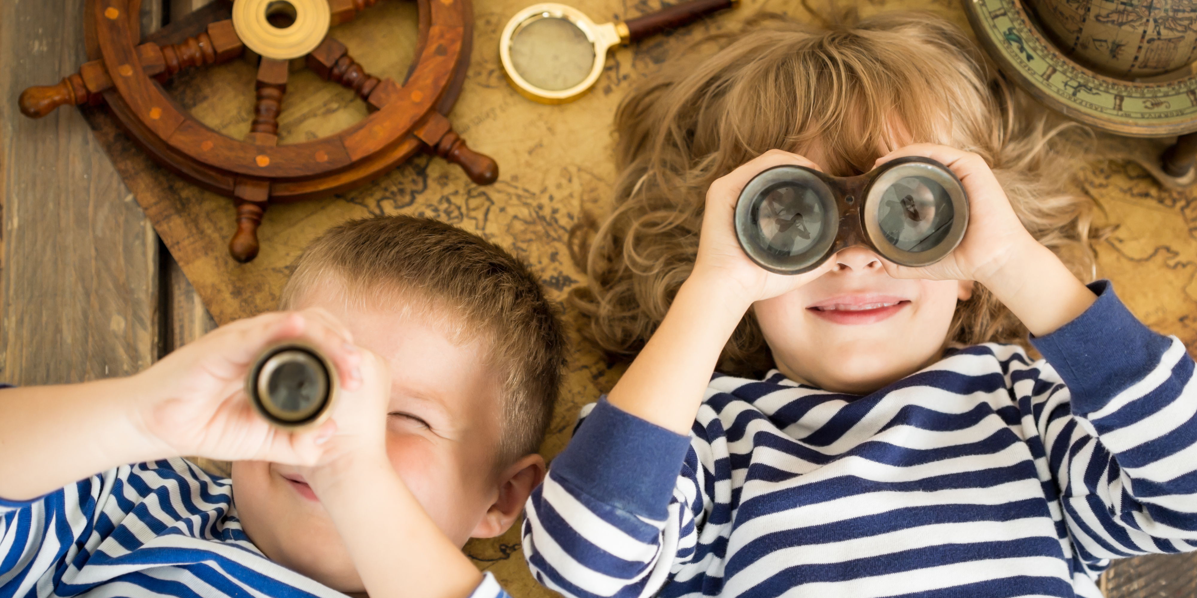 two kids wearing stripes looking out binoculars 