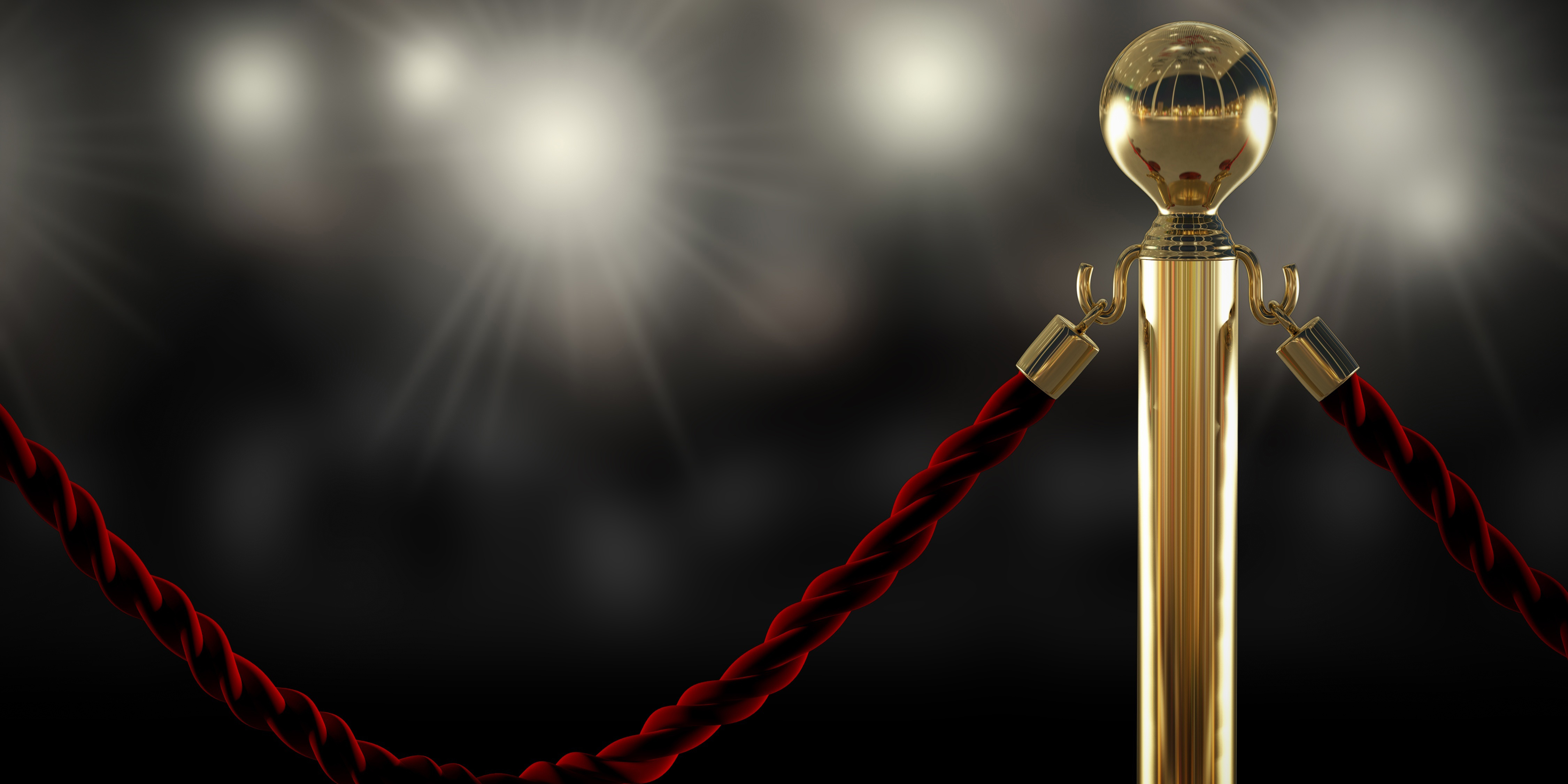 Red rope attached to gold pole with lights in the background